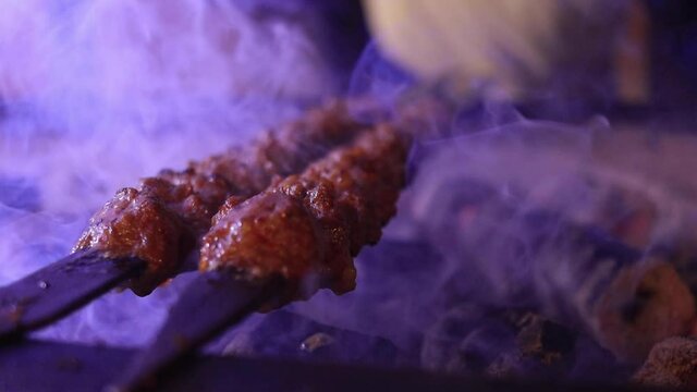 Several raw traditional Turkish shish Adana Kebab skewers that made of meat are lined up over charcoal in barbecue. High quality FullHD footage