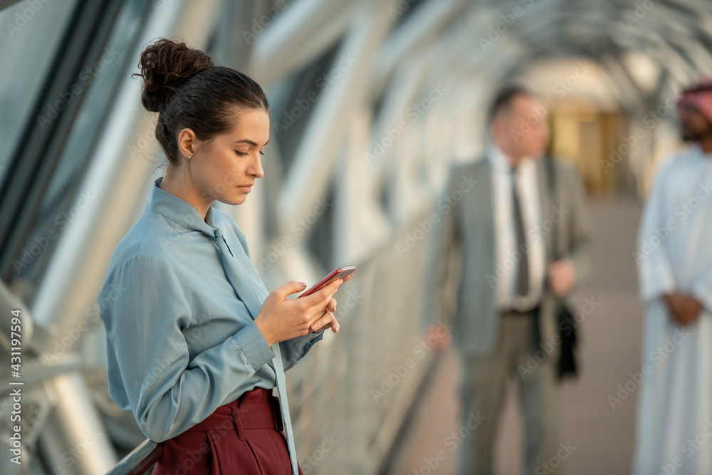 Wall mural elegant woman looking at the phone while standing in front of camera