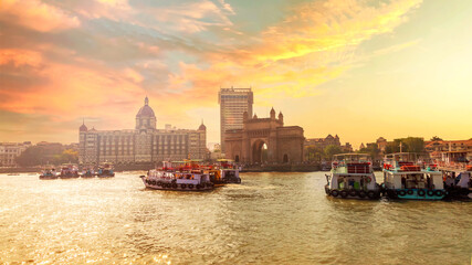 Sunset photo of city scape with The Gateway of India along with Taj and boats as seen from the Mumbai Harbour in Mumbai, Maharashtra India  with a beautiful warm sky. - obrazy, fototapety, plakaty