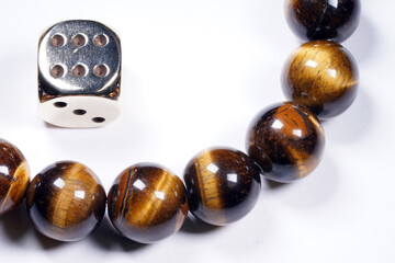 Metal dice and brown beads on a white background top view. Macro. Leisure. Entertainment. Gambling
                       