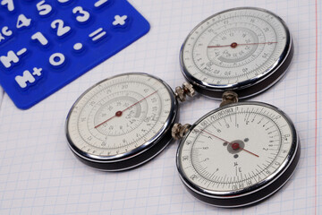 Logarithmic ruler closeup and colorful pencils on a white background. Vintage antique round slide ruler Calculator, felt-tip pens, office, calculating device. Maths. Mathematical. Measuring instrument