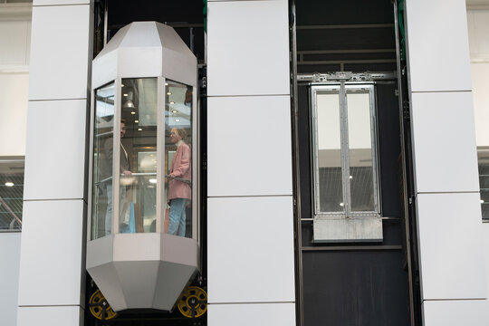 A person standing in moving elevator inside large contemporary mall