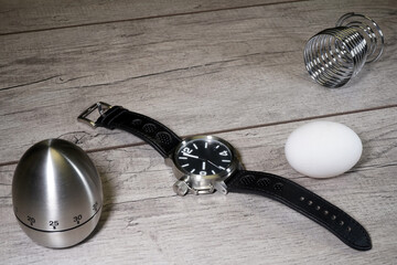 Wrist watch, egg and chronometer on a wooden background. Kitchen alarm clock. Morning. Fast Breakfast                                                             