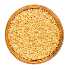 Coarse demerara sugar in a wooden bowl. Crystalline natural raw sugar, a sucrose sugar with distinctive yellow-brown color due to presence of molasses. Close-up from above over white macro food photo.