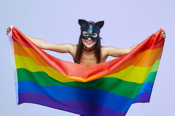 a woman in a cat mask holds a rainbow flag