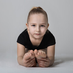 Girl gymnast doing bends to the legs, looking easily at the camera