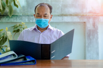 Focused grey-haired elderly man Analyzing Document