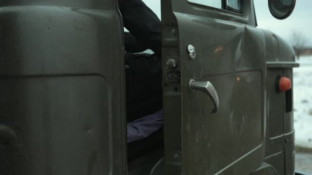 Retro truck, old soviet military truck of world war ii transport. Soviet military vehicle for transporting soldiers. Human hand opens the door of a car dealership