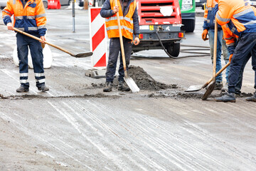 The road workers are cleaning the road on the fenced section of the carriageway.