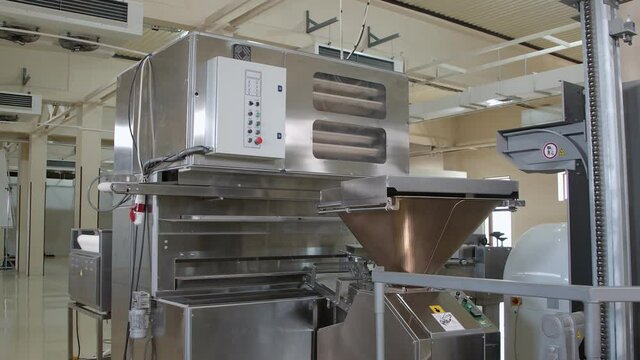 Big  dough machine for mixing, cutting and rolling dough in the middle of large bakery. Slow motion