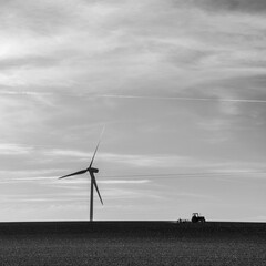 Fototapeta na wymiar le paysage rural de demain: une tracteur en train de labourer un champ au milieu duquel se trouve une éolienne produisant de l'énergie verte durable
