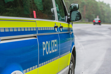 German police car on the highway from the side. Vehicle body on the passenger side with doors, mirrors and lettering Police with yellow and blue paintwork. Emergency bay with asphalt road © Marco