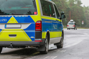 Partial view of a German police car on the highway in rainy weather. Passenger side of the vehicle with the lettering Police on the body in blue and yellow paintwork