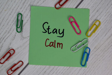 Stay Calm write on sticky notes isolated on Wooden Table.