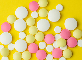 Colored pills on a bright yellow background. Medicine concept and protection againt coronavirus. Selective focus.