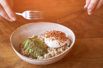 Healthy food at vegan cafe. Green buckwheat with poached egg and avocado. Lifestyle Modern plate with porridge. Cereal breakfast menu. Woman hand holding
