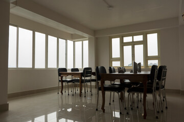 Some empty chairs and dining table of a restaurant with big windows in background. Selective focus.