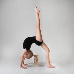 little gymnast demonstrates flexibility and balance in a gymnastic pose bridge with raised leg