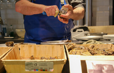 Man opening fresh oysters in a market