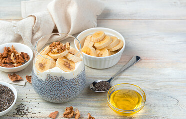 Pudding with chia seeds, banana, honey and nuts on a beige wooden background. Side view, close-up. Healthy food.