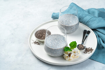 Light, tender and healthy pudding with chia seeds and coconut milk on a gray background. Side view, copy space.