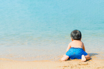 Fototapeta na wymiar 1 year 3 months old baby boy playing sand on the beach,Holidays with baby summer concept.