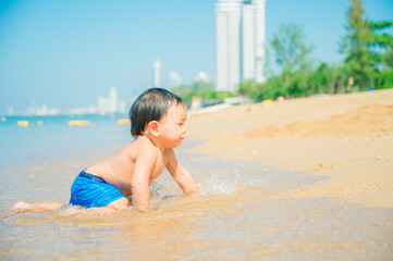 1 year 3 months old baby boy playing sand on the beach,Holidays with baby summer concept.