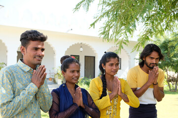 Group of young Indian friends standing outdoors doing namaste