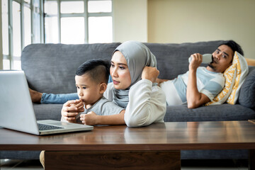 Home Schooling concept, young mother using laptop with her son on her lap Homeschool virtual internet online class