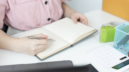 Young Asian woman is writing down the customer's details and addresses on the Clipboard in order to prepare for shipping according to the information, New kind of business for young, Sell online.