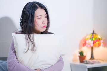 Obraz na płótnie Canvas young Asian woman depressed - young beautiful and sad Chinese girl on bed with pillow feeling unhappy and broken heart suffering depression problem at home bedroom