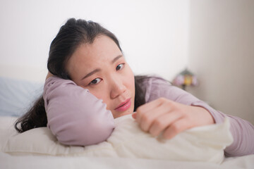 young Asian woman depressed - young beautiful and sad Chinese girl on bed with pillow feeling unhappy and broken heart suffering depression problem at home bedroom
