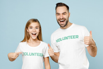 Two young couple teen girl man wears white t-shirt green title volunteer point index fingers on themselves isolated on pastel blue color background Voluntary free team work help charity grace concept
