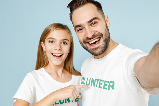 Close up two fun young friends couple teen girl man wears white t-shirt green title volunteer doing selfie isolated on pastel blue color background Voluntary free team work help charity grace concept