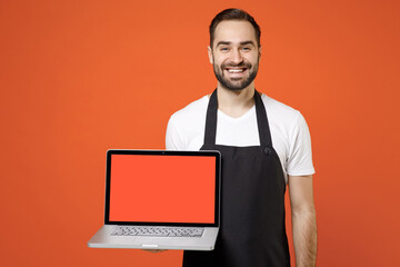 Young man barista bartender barman employee in black apron white t-shirt work in coffee shop using...