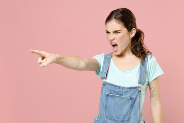 Young strict angry caucasian woman 20s wearing denim clothes blue t-shirt point index finger aside...