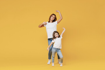 Fototapeta na wymiar Full length happy woman in basic white t-shirt have fun with cute child baby girl 5-6 years old hold hands. Mom little kid daughter isolated on yellow color background studio Mother's Day love family
