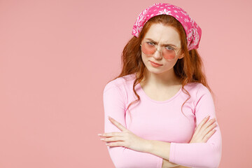 Young shrewd frowning offended serious strict caucasian woman 20s in rose clothes bandana glasses hold hands crssed folded isolated on pastel pink background studio portrait People lifestyle concept.