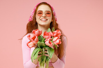 Young smiling happy trendy satisfied caucasian woman 20s wear rose clothes bandana glasses hold...