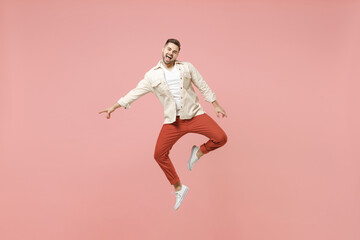 Fototapeta na wymiar Full length side view young smiling excited overjoyed joyful caucasian man 20s in jacket white t-shirt jump high pointing index finger down on workspace area isolated on pastel pink background studio.