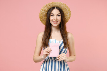 Traveler tourist smiling happy woman 20s in summer clothes hat hold passport tickets isolated on pastel pink background. Passenger traveling abroad on weekends getaway. Air flight journey concept.