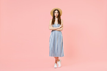 Full length young fun smiling happy caucasian woman in summer clothes striped dress straw hat hold hands crossed folded isolated on pastel pink background studio portrait. People lifestyle concept