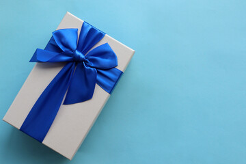 Gift box with blue ribbon on blue paper background. Fathers day present for dad. Top view, copy space