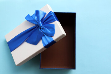 Open gift box with blue ribbon on blue paper background. Fathers day present for dad. Top view,...