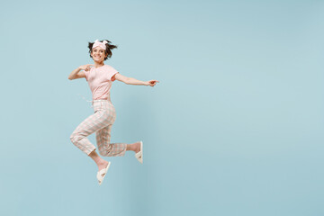 Obraz premium Full length young woman in pajamas jam sleep eye mask rest relax at home jump high point index finger aside workspace area isolated on pastel blue background studio. Good mood night bedtime concept
