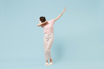 Full length young woman in pajamas jam sleep eye mask rest relax at home do dab hip hop dance hands move gesture youth sign cover face isolated on pastel blue background Good mood bedtime concept.