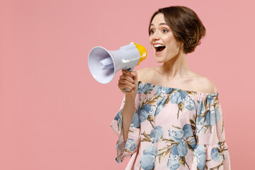 Young fun happy expressive satisfied caucasian woman 20s with short hairdo wearing trendy stylish blouse screaming shouting in megaphone aside isolated on pastel pink color background studio portrait
