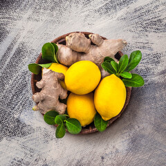 Lemons and ginger in wooden jar with green leaves ready to eat kitchen table overhead arrangement studio shot on painted gray background