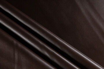 surface with folds of artificial leather for sewing clothes dark chocolate color, background