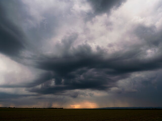 Dramatic sky of heavy gray clouds and sunbeams